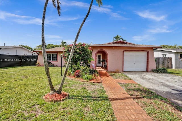ranch-style house with fence, an attached garage, aphalt driveway, stucco siding, and a front yard