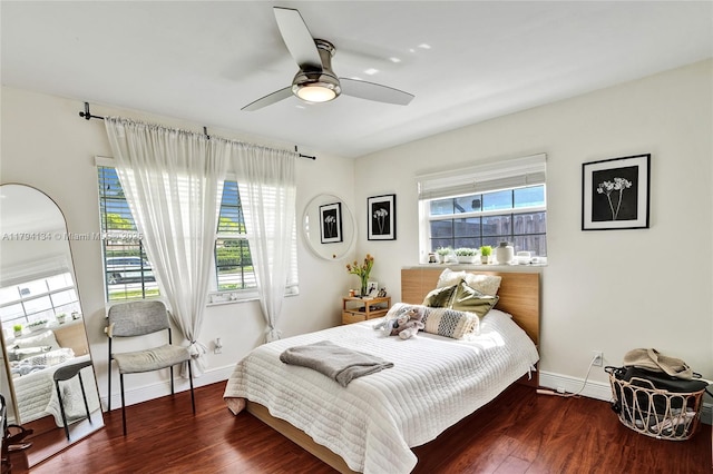 bedroom featuring baseboards, ceiling fan, wood finished floors, and multiple windows