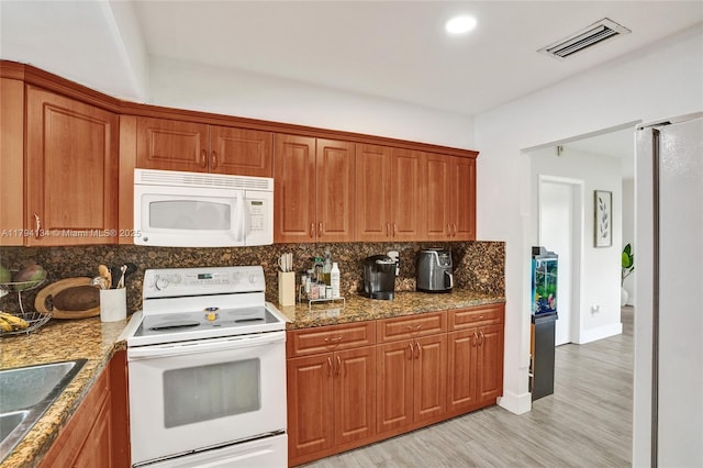 kitchen featuring visible vents, white appliances, tasteful backsplash, a sink, and light wood-style flooring