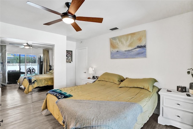 bedroom with ceiling fan, access to outside, wood finished floors, and visible vents