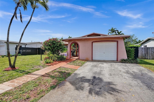 ranch-style home with driveway, a garage, fence, a front lawn, and stucco siding