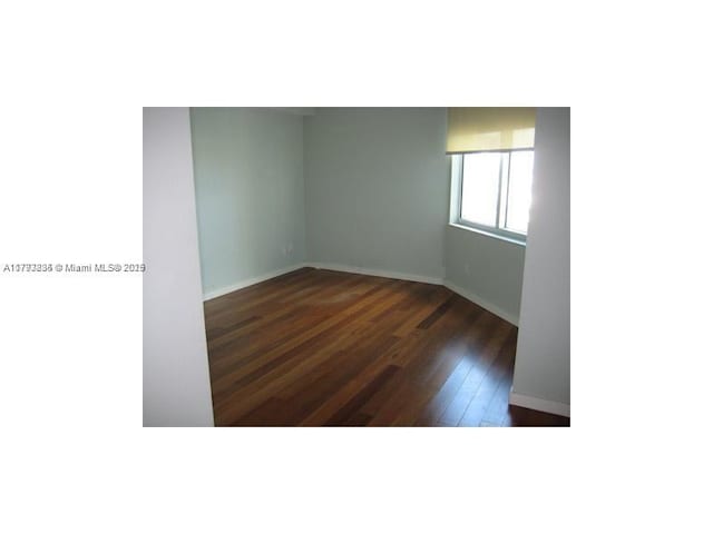 spare room featuring baseboards and hardwood / wood-style flooring