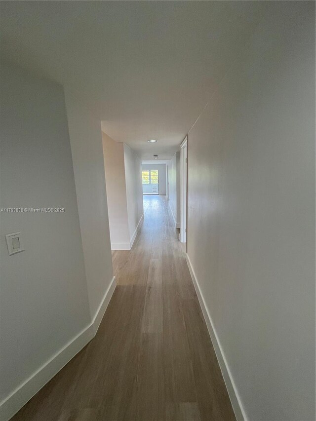 hallway featuring baseboards and wood finished floors