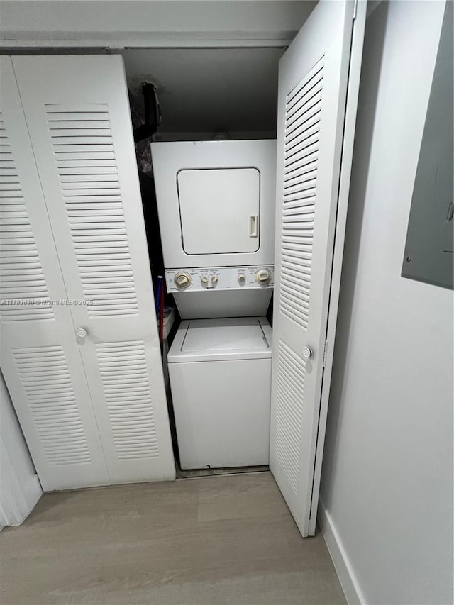 laundry area featuring light wood-style floors, stacked washer and clothes dryer, electric panel, and laundry area
