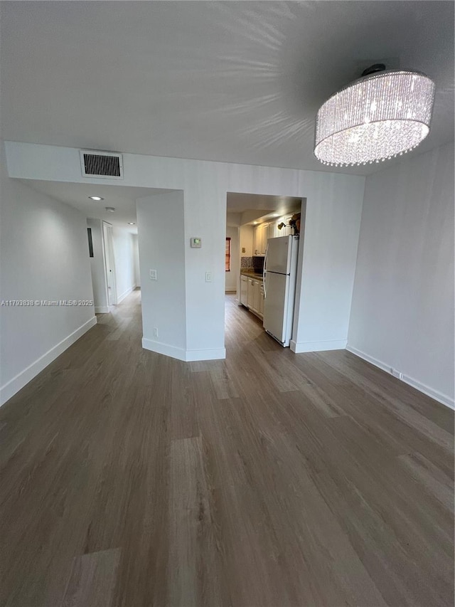 interior space featuring visible vents, baseboards, dark wood-type flooring, and an inviting chandelier