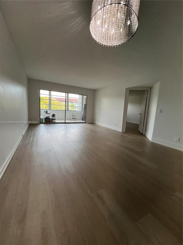 interior space featuring baseboards, wood finished floors, and a notable chandelier