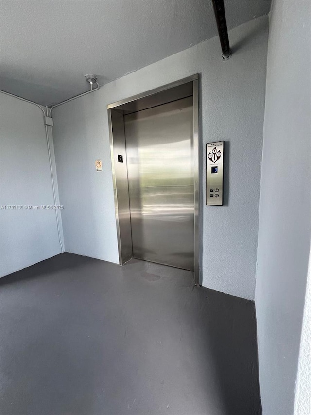 spare room featuring elevator and finished concrete floors
