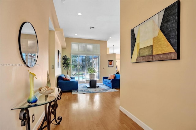 hallway with baseboards, recessed lighting, wood finished floors, and visible vents