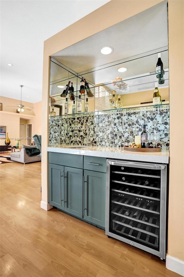 bar featuring indoor bar, a sink, light wood finished floors, and wine cooler