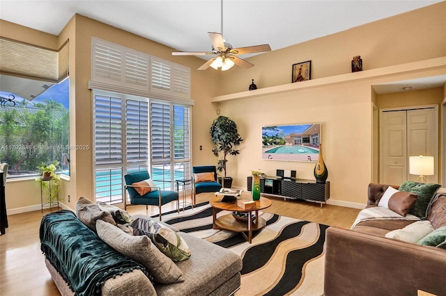 living room with baseboards, ceiling fan, and light wood-type flooring