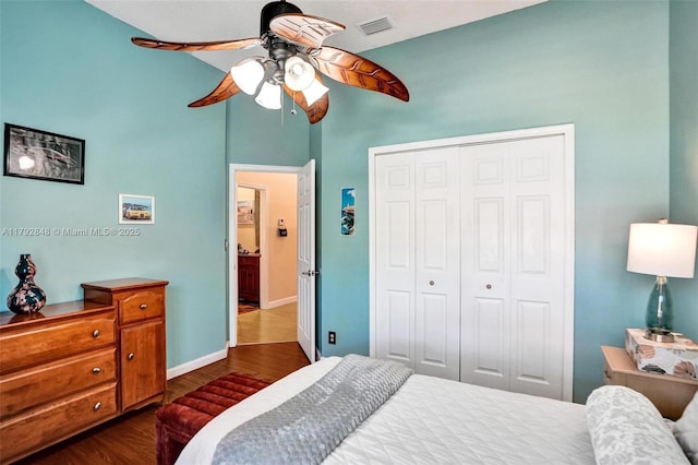 bedroom featuring dark wood-style flooring, a ceiling fan, baseboards, visible vents, and a closet