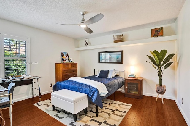 bedroom featuring a textured ceiling, ceiling fan, baseboards, and wood finished floors