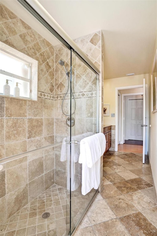 bathroom featuring vanity, a shower stall, and stone finish flooring
