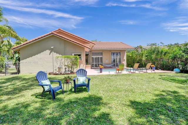 rear view of property with a patio area, an outdoor pool, stucco siding, and a tiled roof