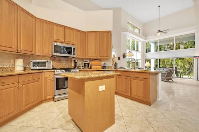 4123 W Lake Estates Dr, Davie, FL 33328 - kitchen with appliances with stainless steel finishes, a towering ceiling, a sink, a center island, and decorative backsplash