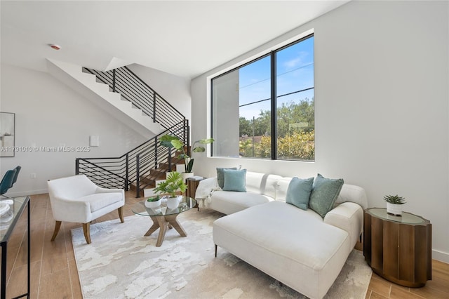 living area with baseboards, wood finished floors, and stairway