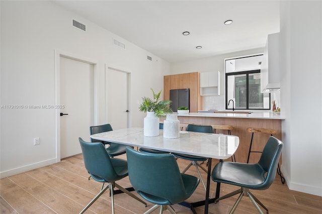 dining space featuring baseboards, visible vents, and light wood-style flooring