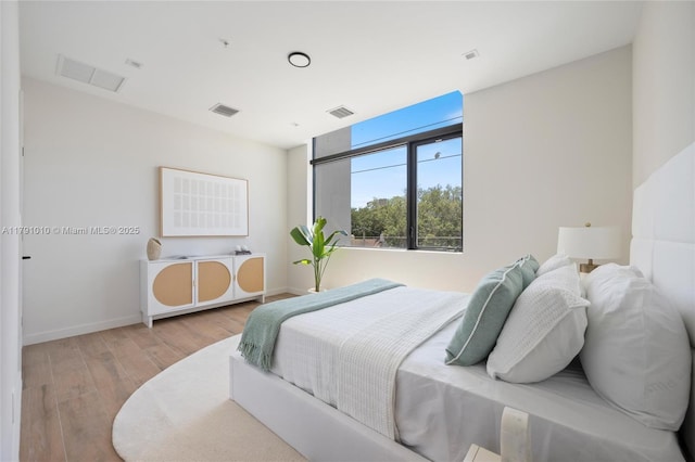 bedroom with baseboards, wood finished floors, and visible vents
