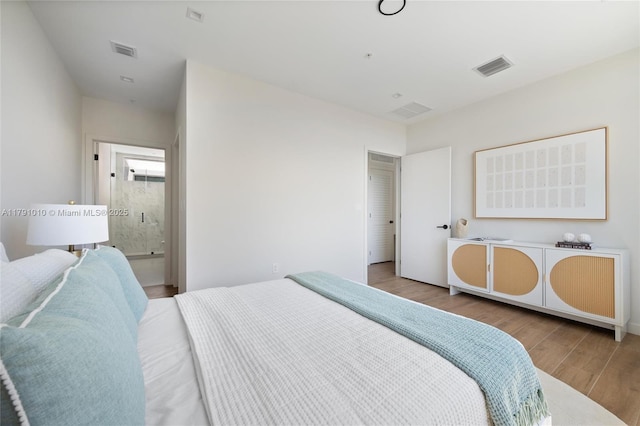 bedroom with visible vents, wood finished floors, and ensuite bathroom
