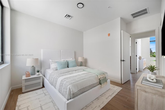 bedroom featuring baseboards, visible vents, and wood finished floors