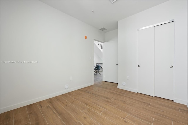 unfurnished bedroom featuring baseboards, light wood-style flooring, and visible vents