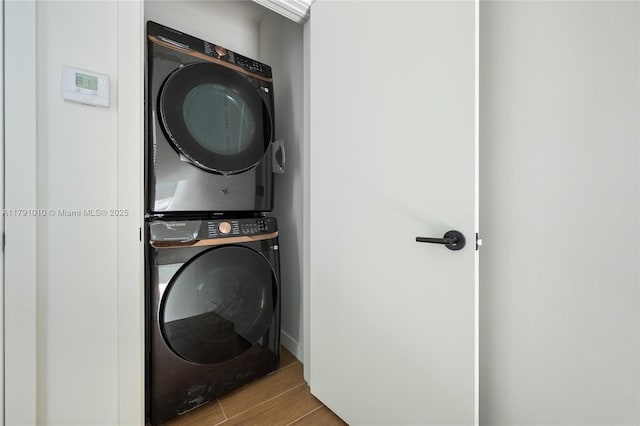 laundry area with laundry area, wood finished floors, and stacked washer / dryer