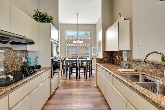 7649 Briar Cliff Cir, Lake Worth, FL 33467 - kitchen with black electric stovetop, wall oven, a sink, a chandelier, and under cabinet range hood