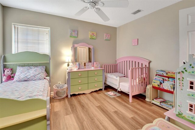 7649 Briar Cliff Cir, Lake Worth, FL 33467 - bedroom featuring light wood-style flooring, a ceiling fan, and a nursery area