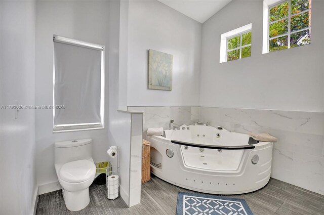 7649 Briar Cliff Cir, Lake Worth, FL 33467 - bathroom featuring tile walls, a whirlpool tub, toilet, and a wainscoted wall