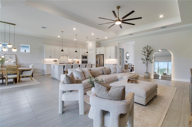 9657 Mosler Trl, Lake Worth, FL 33467 - living room with a tray ceiling, a ceiling fan, ornamental molding, light tile patterned floors, and arched walkways