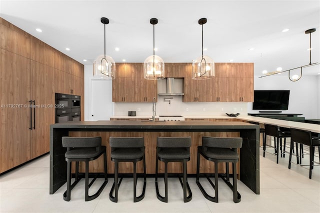 kitchen featuring dark countertops, modern cabinets, a breakfast bar area, a sink, and light tile patterned floors