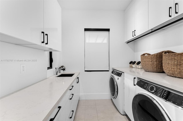 washroom featuring cabinet space, a sink, baseboards, light tile patterned floors, and washing machine and dryer