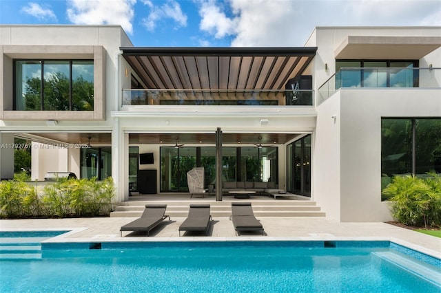 rear view of property with outdoor lounge area, a balcony, a patio area, and stucco siding