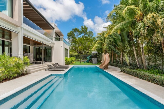 13180 Old Cutler Rd, Pinecrest, FL 33156 - outdoor pool with a water slide, a playground, and a patio