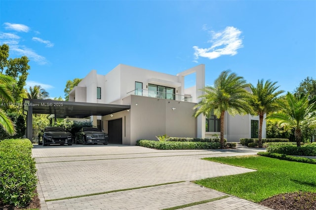 view of front of property with stucco siding, a garage, decorative driveway, a front lawn, and an attached carport