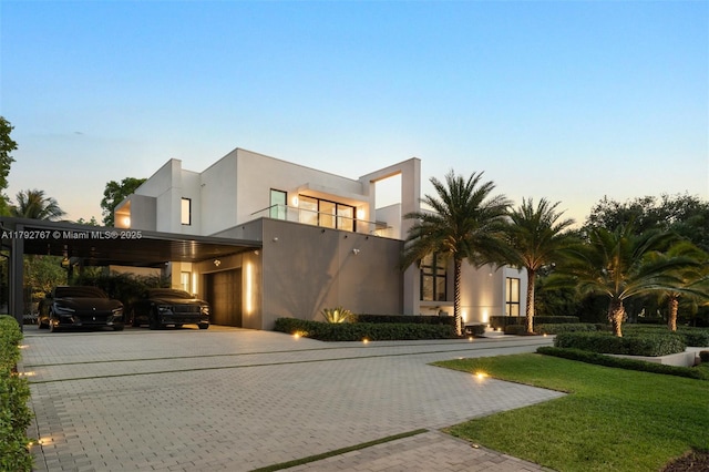 contemporary house featuring a yard, an attached garage, driveway, and stucco siding
