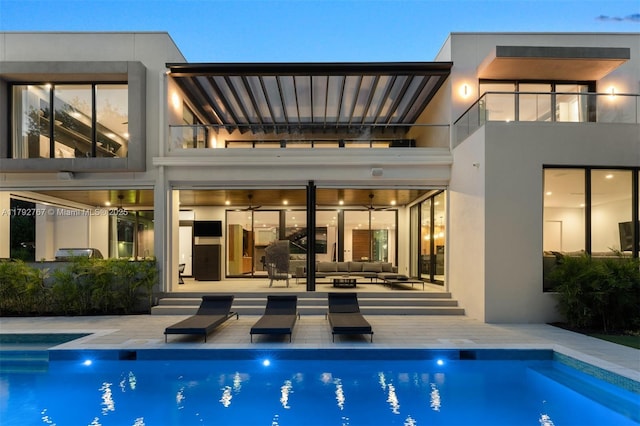 back of house with outdoor lounge area, a balcony, a patio area, and an outdoor pool