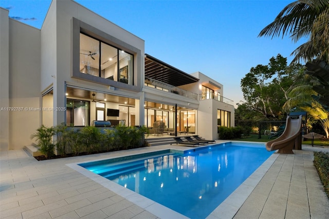 rear view of house featuring a patio, an outdoor pool, stucco siding, and a balcony