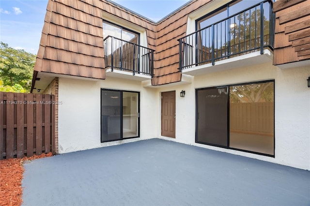 853 SW 118th Ter, Davie, FL 33325 - rear view of house with fence, stucco siding, a balcony, a patio, and mansard roof