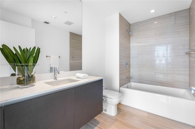 bathroom featuring visible vents, shower / tub combination, wood finished floors, vanity, and toilet