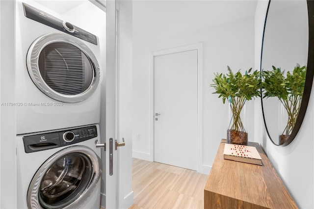 clothes washing area featuring stacked washer and dryer, laundry area, and light wood-style floors