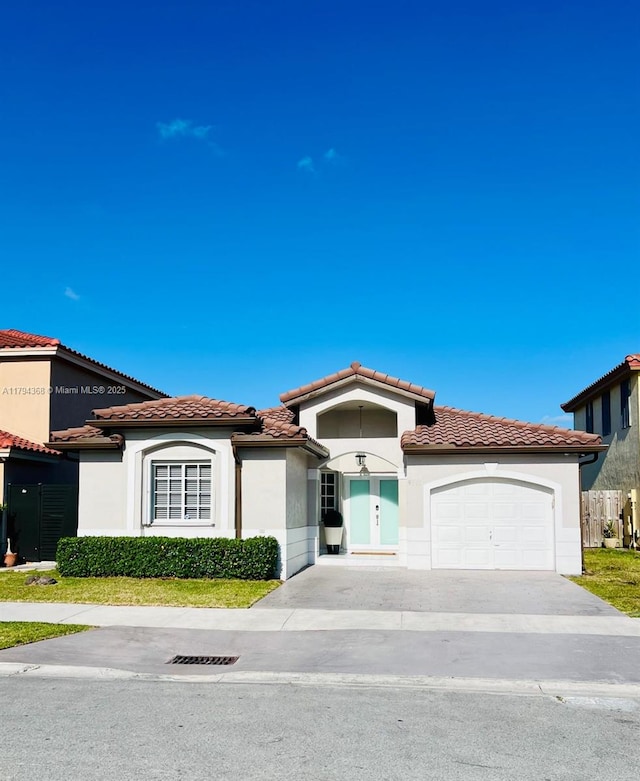 mediterranean / spanish-style home with an attached garage, stucco siding, and a tiled roof