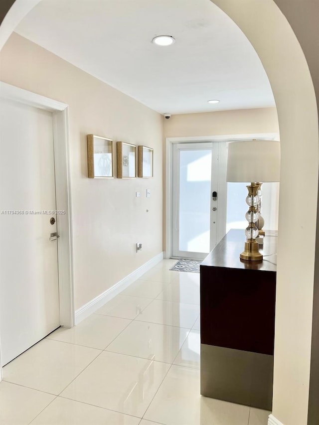 foyer entrance with arched walkways, baseboards, recessed lighting, and light tile patterned flooring
