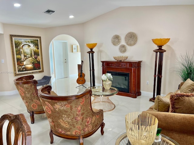 sitting room with visible vents, arched walkways, tile patterned floors, lofted ceiling, and a glass covered fireplace
