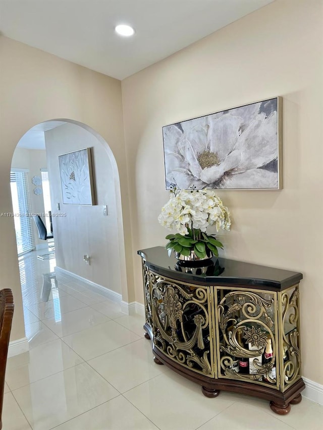 hallway with arched walkways, baseboards, recessed lighting, and light tile patterned flooring
