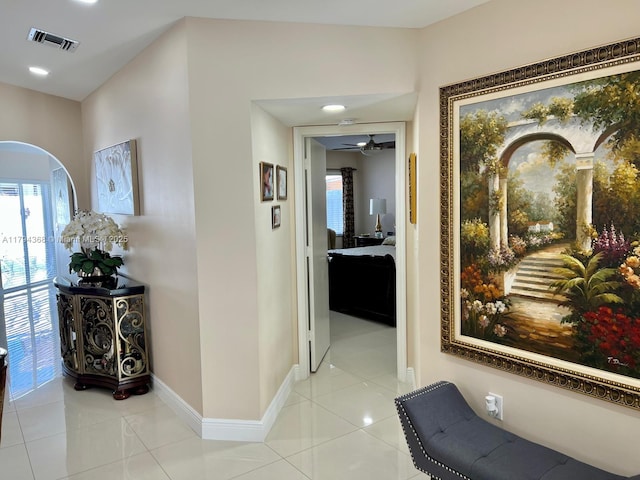 corridor with light tile patterned floors, baseboards, a wealth of natural light, and visible vents