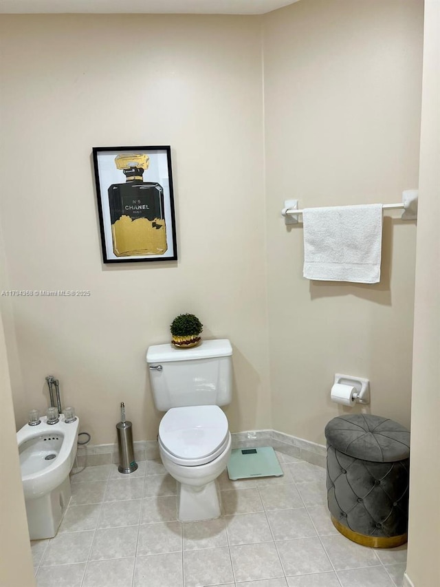 half bathroom featuring toilet, baseboards, a bidet, and tile patterned flooring