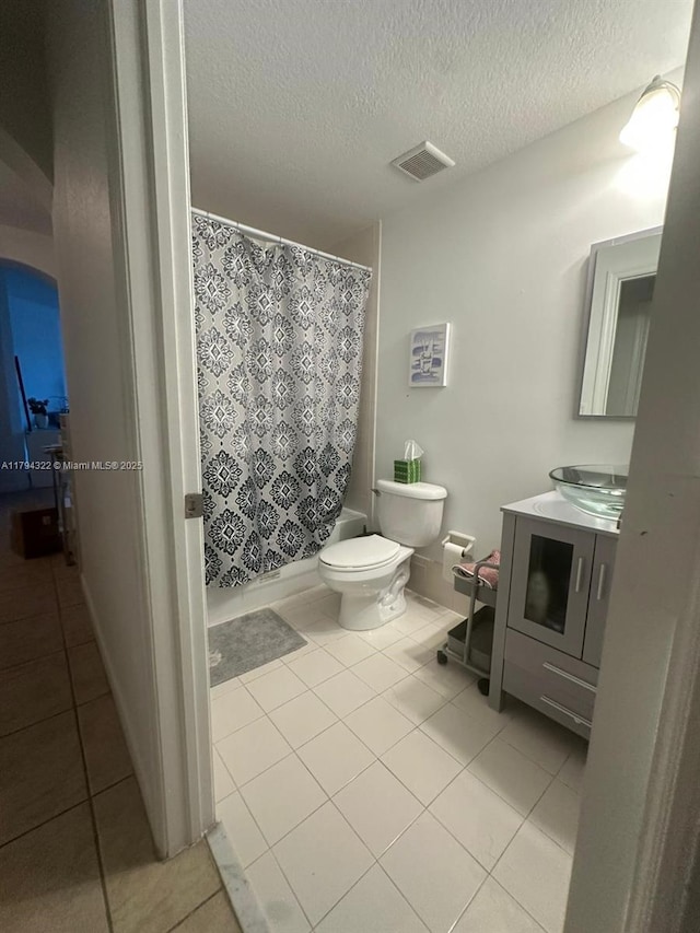 full bathroom with toilet, tile patterned floors, visible vents, and curtained shower