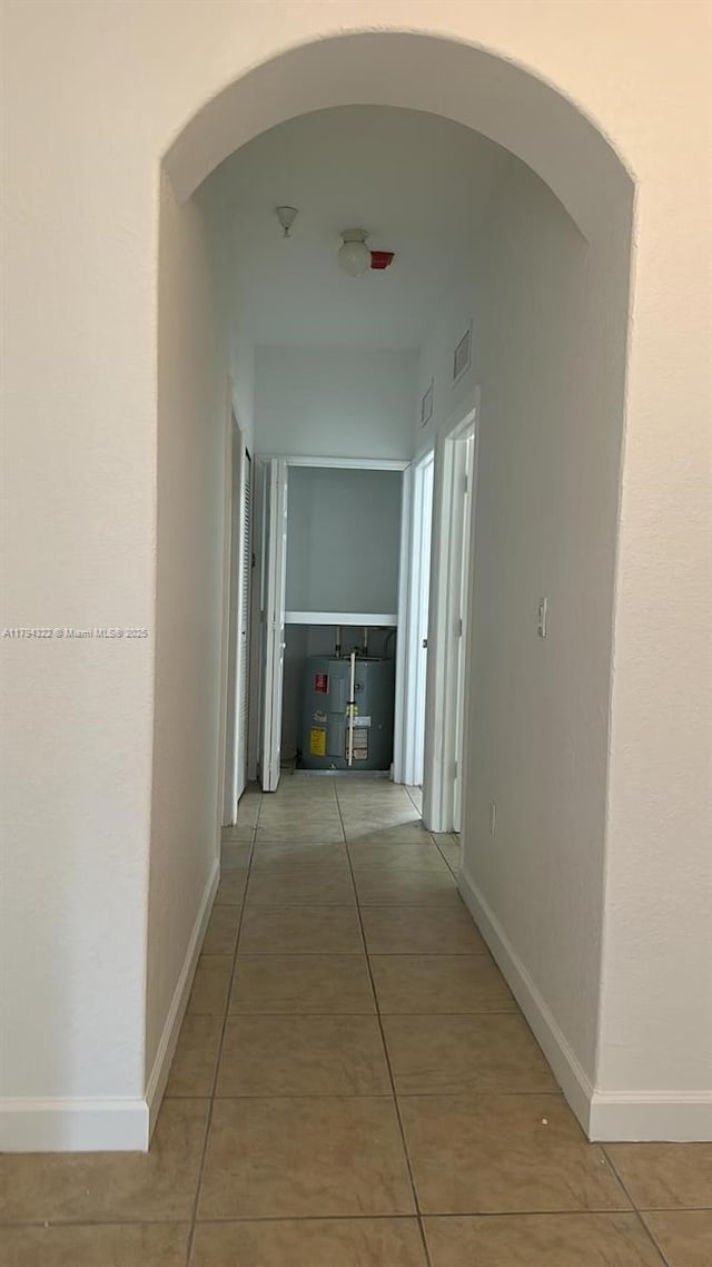 corridor featuring arched walkways, visible vents, and light tile patterned floors