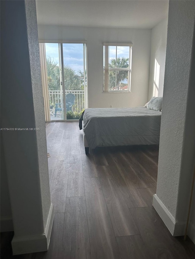 bedroom featuring a textured wall, wood finished floors, and access to exterior